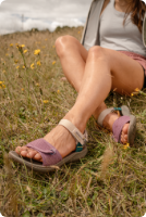 Person sitting in grass wearing Merrell sandals.